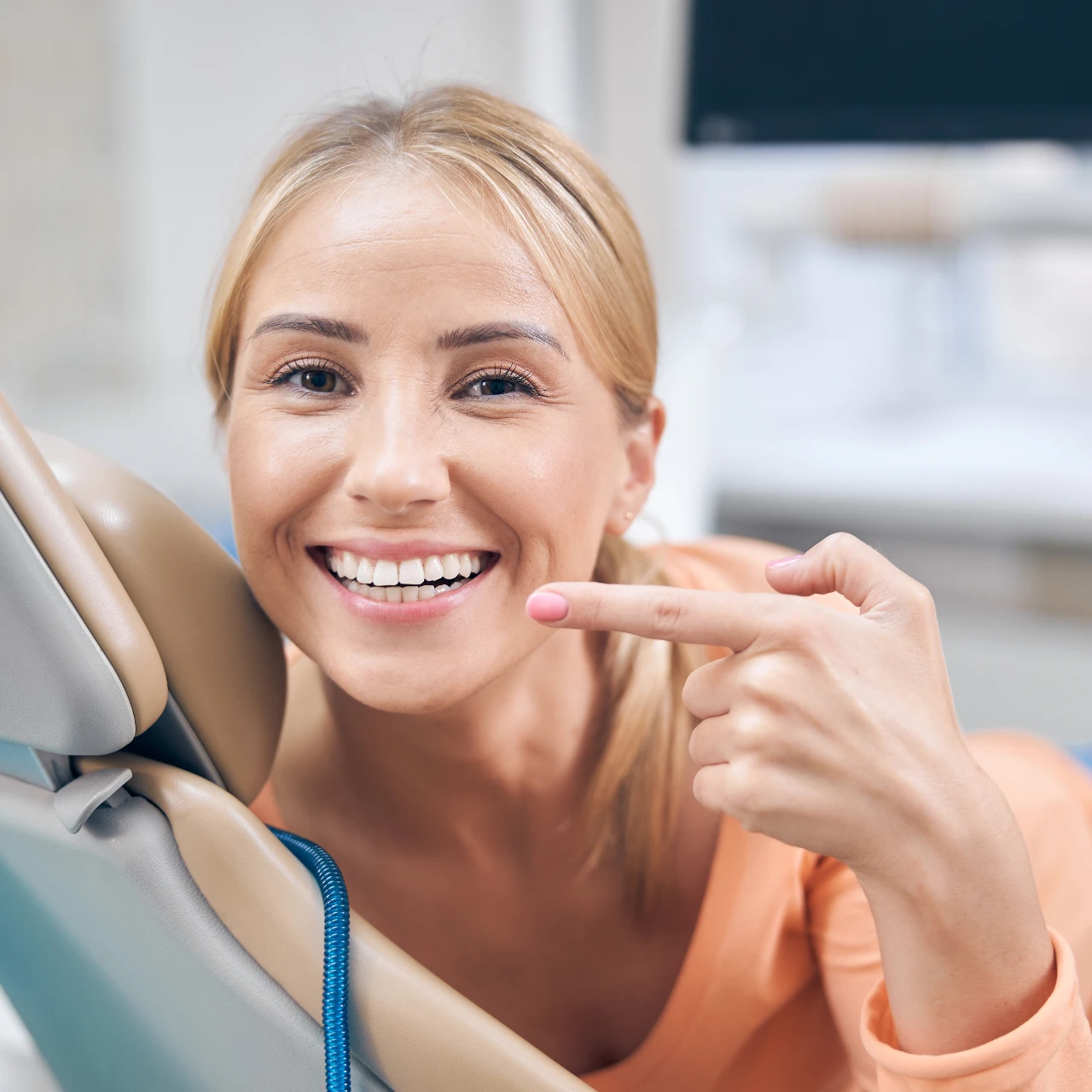 woman smiling and pointing to teeth | cosmetic dentistry in orange county
